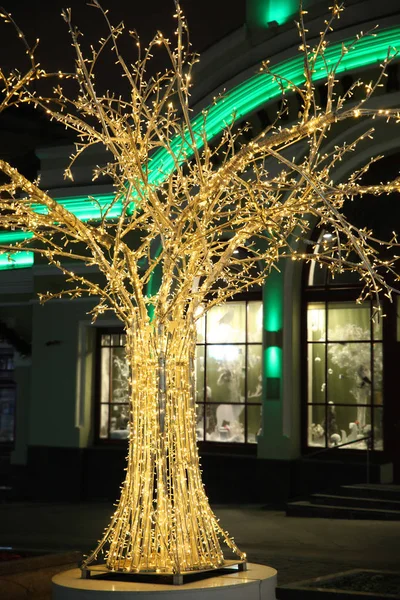 Street decorations, Shiny Golden ornamental tree in led lights on the background of the house
