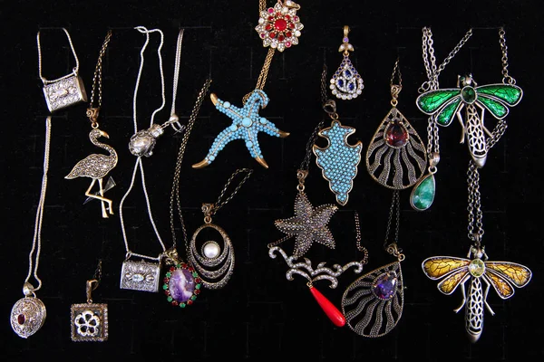 Vintage chains with various jewelry pendants and in the form of starfish, dragonflies on a dark background close-up
