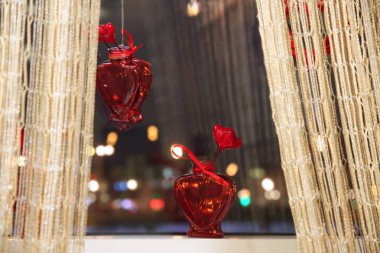 Pencere kenarında asılı ve bir kırmızı kalp şeklinde küçük bir vazo ayakta ışıklar karşı
