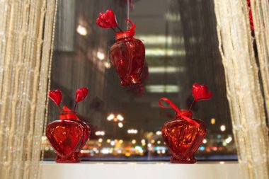 Kalpler penceresinde şeklinde küçük bardak kırmızı vazo. Sevgililer günü için kırmızı kalpler ile şenlikli pencere dekorasyon