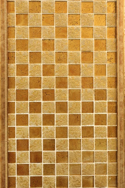 Wall decoration with fine decorative tiles of gold color with a pattern