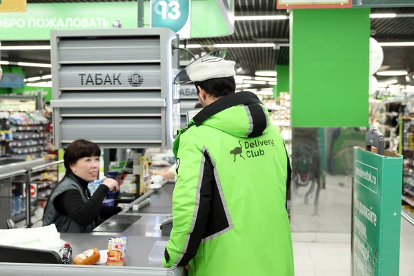 Человек из службы доставки продуктов питания "Delivery-club" оплачивает пурк — стоковое фото