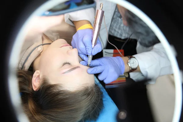 Tatuagem de sobrancelha faz um mestre no rosto de uma linda garota — Fotografia de Stock