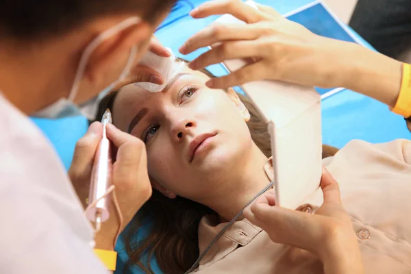 Belle fille regarde ses sourcils à la fin de la procédure — Photo