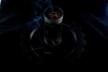 Arka planda tütsü dumanı olan cam bir şişedeki çiçekten Çin çayı demlemek.