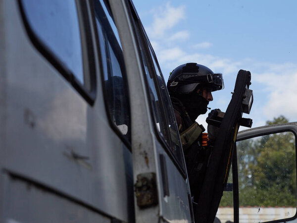 Солдаты спецназа со щитом идут на штурм из машины