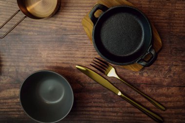 Ahşap zemin üzerinde yemek takımları, çatal bıçak takımı ve sofra takımı.