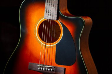 Akustik gitar. Davanın bir parçası ve siyah arkaplanda dizgiler.
