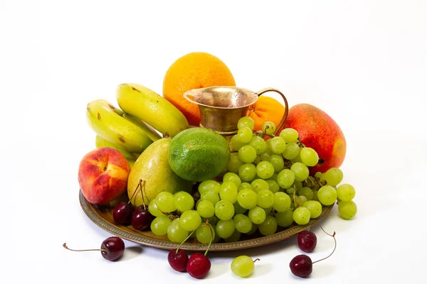 Assortment of exotic fruits on a tray with a jug with splashes of water on a white background. Healthy lifestyle concept.