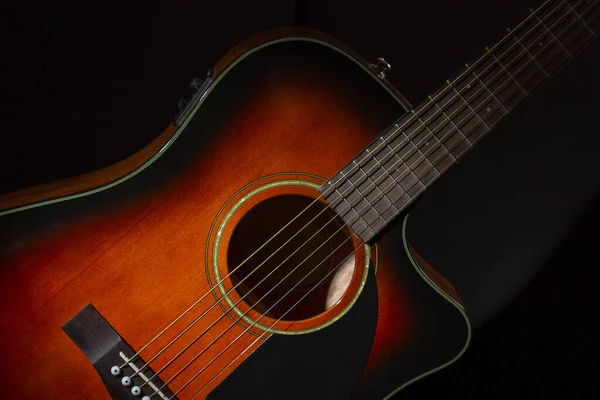 Acoustic guitar. Part of the case and strings on a black background.