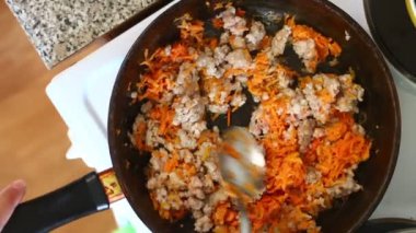 Adam bir tavada dolma ve doğranmış havuç karışımları.