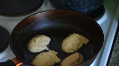 Bir kadın bir sıcak tava üzerinde hamur bırakır. Krep hazırlanması.