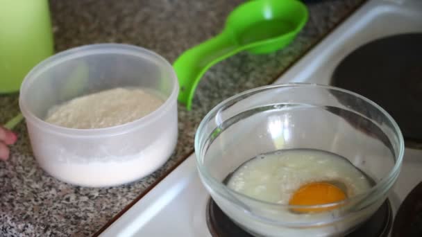 这个女人把糖和盐加在容器里的鸡蛋上 一个女人正在为煎饼准备面团 — 图库视频影像