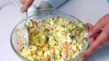 Rus et salatası sebze ve mayonez. Bir kadın bir haşlanmış yumurta bir kesme tahtası üzerinde keser..
