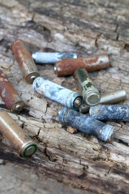 Kullanılmış piller, korozyon ile kaplı. Farklı şekil ve boyutlarda. ahşap kütük kenarında yalan. Çevre koruma, geri dönüşüm.
