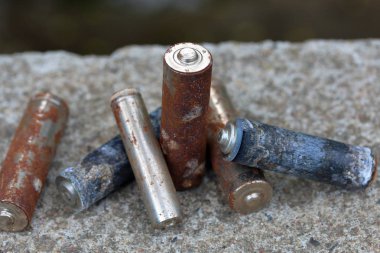Kullanılmış piller, korozyon ile kaplı. Farklı şekil ve boyutlarda. bir beton yüzey üzerinde yalan. Çevre koruma, geri dönüşüm.