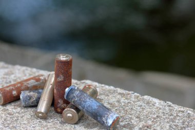 Kullanılmış piller, korozyon ile kaplı. Farklı şekil ve boyutlarda. bir beton yüzey üzerinde yalan. Çevre koruma, geri dönüşüm.