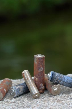 Kullanılmış piller, korozyon ile kaplı. Farklı şekil ve boyutlarda. bir beton yüzey üzerinde yalan. Çevre koruma, geri dönüşüm.