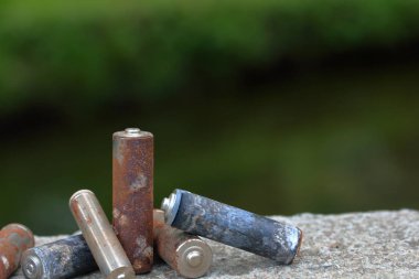 Kullanılmış piller, korozyon ile kaplı. Farklı şekil ve boyutlarda. bir beton yüzey üzerinde yalan. Çevre koruma, geri dönüşüm.