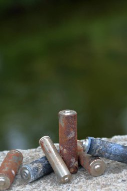 Kullanılmış piller, korozyon ile kaplı. Farklı şekil ve boyutlarda. bir beton yüzey üzerinde yalan. Çevre koruma, geri dönüşüm.