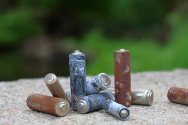 Kullanılmış piller, korozyon ile kaplı. Farklı şekil ve boyutlarda. bir beton yüzey üzerinde yalan. Çevre koruma, geri dönüşüm.