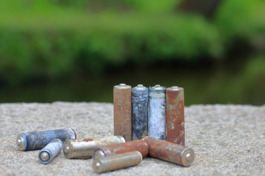 Kullanılmış piller, korozyon ile kaplı. Farklı şekil ve boyutlarda. bir beton yüzey üzerinde yalan. Çevre koruma, geri dönüşüm.