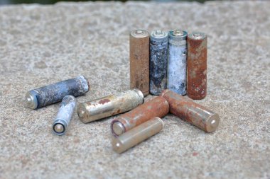 Kullanılmış piller, korozyon ile kaplı. Farklı şekil ve boyutlarda. bir beton yüzey üzerinde yalan. Çevre koruma, geri dönüşüm.