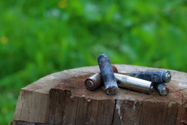 Kullanılmış piller, korozyon ile kaplı. Farklı şekil ve boyutlarda. ahşap kütük kenarında yalan. Çevre koruma, geri dönüşüm.