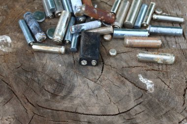 Kullanılmış piller, korozyon ile kaplı. Farklı şekil ve boyutlarda. ahşap kütük kenarında yalan. Çevre koruma, geri dönüşüm.