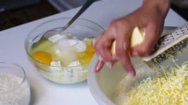 Bir kadın bir mermer kek yapmak için malzemeleri karıştırır. Bir hamur içine rende biler ezmesi. Tablo yanında diğer unsurlarıdır.