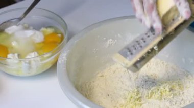 Bir kadın bir mermer kek yapmak için malzemeleri karıştırır. Bir hamur içine rende biler ezmesi. Tablo yanında diğer unsurlarıdır.