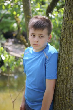 Nehir kenarında bir parkta yürürken bir genç bir fotoğrafçı için poz veriyor.