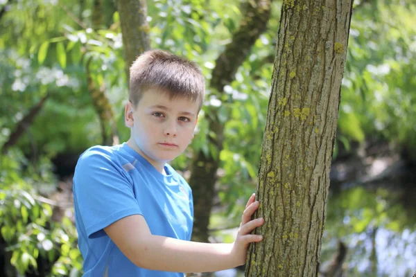 Bir gencin parkta yürürken bir fotoğrafçı için poz veriyor. Düşünceli görünüm.