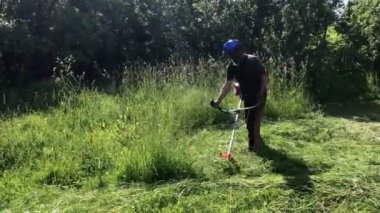 Bir adam bir benzin örgü ile çalışıyor. Oblique yan yana önde gelen tarama alanı, yatıyor. Yüzünde bir koruyucu net koymak.