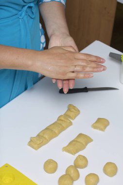 Masanın üzerine hamur parçalarıdır. Bir kadın topları onları dışarı rulo.