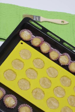 Fırın tepsisine bir silikon kalıp ile bir hamur olduğunu. Ayrıca küçük kağıt formları ile hamur dolu.