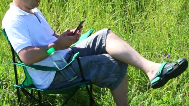 Hombre Sienta Una Silla Picnic Prado Iluminado Está Descansando Trabajando — Vídeo de stock