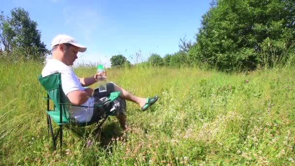 一个男人坐在折叠式野餐椅上 用智能手机工作 然后他起床离开了 四周是挥舞着草 倾斜的风 — 图库视频影像