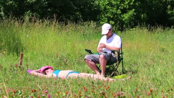 Girl Swimsuit Sunbathing Lawn Next Her Picnic Chair Man Sits — Stock Video