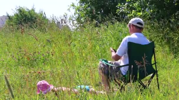 Girl Swimsuit Sunbathing Lawn Next Her Picnic Chair Man Sits — Stock Video