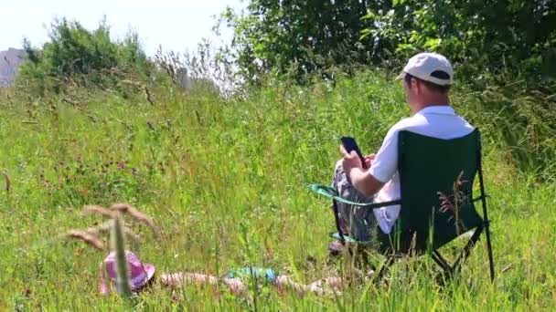 Dívka Plavkách Opalování Trávníku Vedle Křesle Piknik Muž Sedí Hraje — Stock video