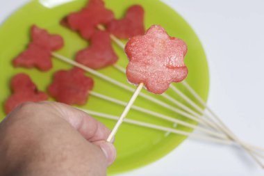 Karpuz hamuru parçalarını bir damga ile kesilir. Onlar farklı biçimleri verilmiştir. Yaylı piknik için şiş üzerinde. Adam bir şiş elinde tutuyor.
