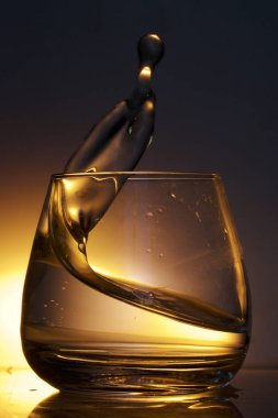 Bir bardak sıvı sıçrama. Renkli bir arka plan üzerine fotoğraflandı. Arka ışık kontrol.