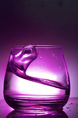 Bir bardak sıvı sıçrama. Renkli bir arka plan üzerine fotoğraflandı. Arka ışık kontrol.