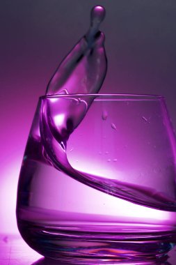 Bir bardak sıvı sıçrama. Renkli bir arka plan üzerine fotoğraflandı. Arka ışık kontrol.