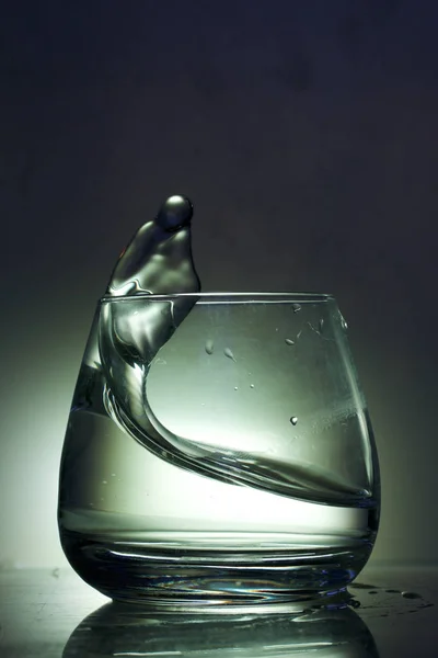Splash Cieczy Szklance Sfotografowany Kolorowym Tle Sterowanie Podświetleniem — Zdjęcie stockowe