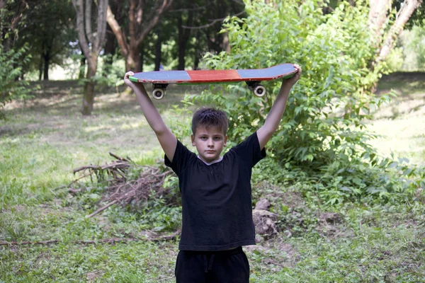 Bir kaykay ile bir genç. Bir paten elinde tutan.