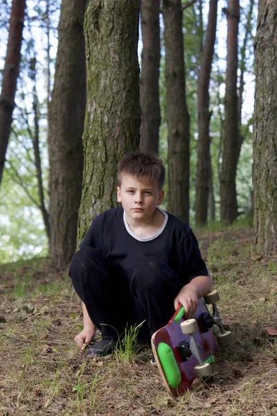 Bir kaykay ile bir genç. Bir paten elinde tutan.