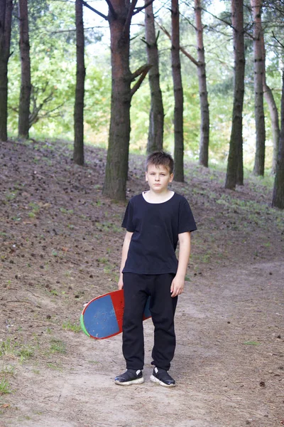 Bir kaykay ile bir genç. Bir paten elinde tutan.