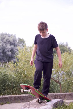Bir genç bir kaykay üzerinde duruyor.